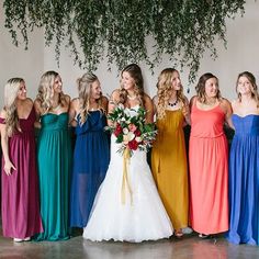 a group of women standing next to each other in long dresses and holding bouquets