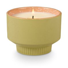 a small yellow candle holder with a single lit candle in the center on a white background