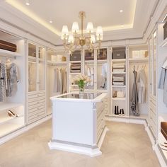 a walk in closet filled with lots of white shelves and drawers next to a chandelier