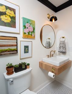 a bathroom with pictures on the wall and a sink in the corner next to a toilet