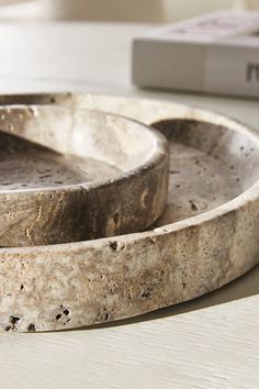 two stone bowls sitting on top of a table next to a book and remote control