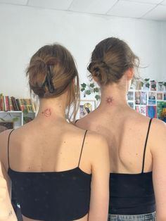 two women with tattoos on their backs looking in the mirror