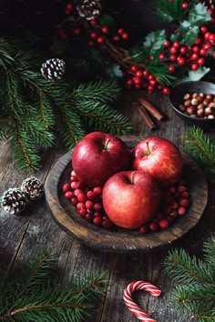 apples and berries in a wooden bowl with candy canes