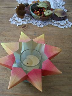 an origami star candle holder on a wooden table next to a lace doily