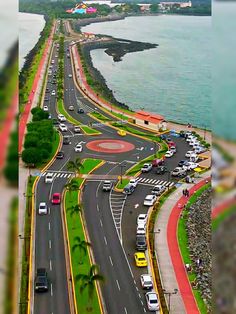 an aerial view of a street with cars on it and the ocean in the background