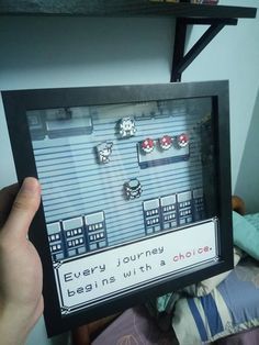 someone is holding up a video game frame with some earrings on it in front of a bed