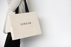 a woman carrying a shopping bag with the word inwear printed on it, against a white background