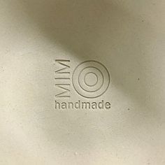 a close up of a white plate with the name mia handmade on it