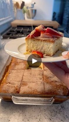 someone holding a piece of cheesecake on a plate with strawberries in the middle