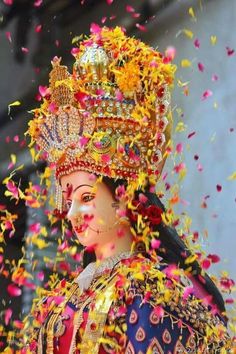 a woman dressed in an elaborate costume surrounded by confetti and streams of petals