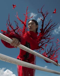 a woman in a red dress is holding a white pole