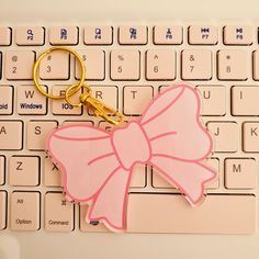 a pink bow keychain sitting on top of a keyboard