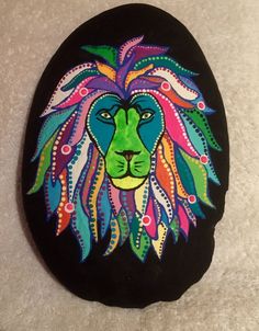 a painted rock with a colorful lion's head on the front and back side