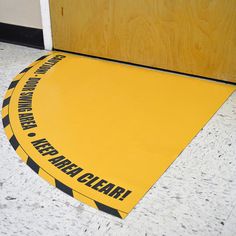 a yellow caution sign sitting on the floor in front of a door with black and white stripes