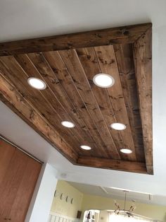 a kitchen with wooden ceiling and lights above it