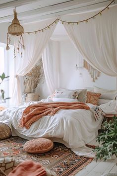 a bed with white sheets and orange blankets on top of it next to a potted plant