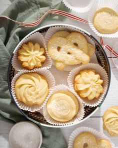 some cookies are sitting in paper cups on a table with other pastries around them