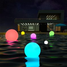 there are many different colored balls floating in the water near a building and umbrellas