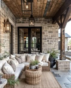 an outdoor living area with wicker furniture and stone walls, wood ceilinging and large windows