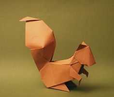 an origami animal made out of paper on a green background with the shape of a bird