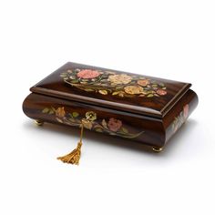 a wooden box with flowers painted on the side and tassels hanging from it