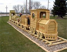 a train made out of wood sitting in the grass