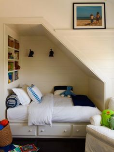 a bedroom with a bed, chair and bookshelf under the slanted roof