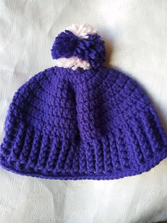 a purple knitted hat with a white pom - pom