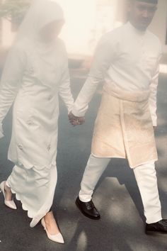 two people dressed in white holding hands