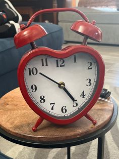 a red alarm clock sitting on top of a wooden table