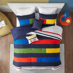 a bed with colorful comforters and pillows on top of it in a child's room