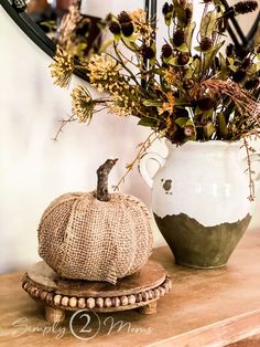 a white vase filled with flowers sitting on top of a wooden table next to a pumpkin