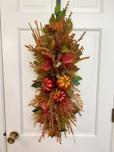 a white door with a wreath on it and autumn decorations hanging from the front door