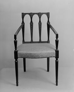 a black and white photo of a chair with an upholstered back, in front of a gray background