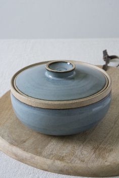 a bowl with a lid on a wooden platter