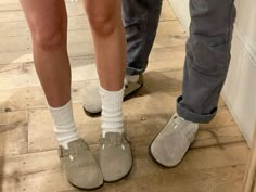 two people standing next to each other wearing slippers and socks with their feet on the ground