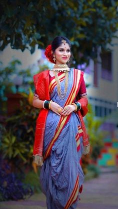 a woman in a blue and red sari is walking down the street with her hand on her hip