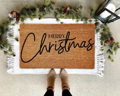 a person standing in front of a door mat that says merry christmas