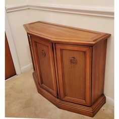 a wooden cabinet with wicker doors and drawers on the bottom shelf in a room