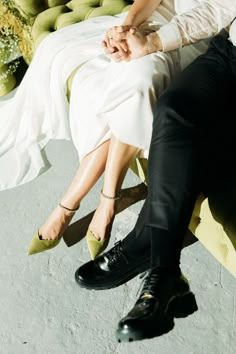 a man and woman sitting on top of a yellow bench next to each other with their hands together