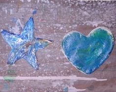 two blue hearts and a star on a wooden surface with paint splattered over them