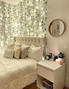 a white bed sitting next to a night stand with lights on the wall behind it