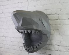 a paper sculpture of a shark with its mouth open on a brick wall in front of a white brick wall