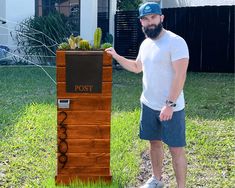 a man standing next to a wooden post with cacti in it