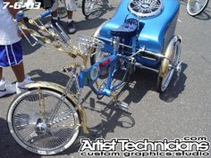 a blue and gold bike parked in front of a car on the side of the road