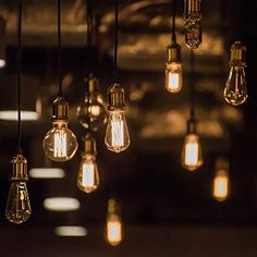 many light bulbs hanging from the ceiling in a dark room with other lights on it