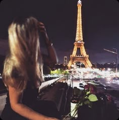 a woman sitting in front of the eiffel tower with her hair blowing in the wind