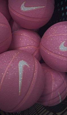 pink nike basketballs are stacked in a basket