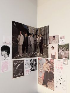 a group of men standing next to each other in front of a wall with pictures on it