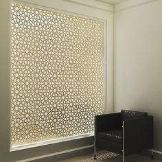 a black chair sitting in front of a window next to a white wall and floor